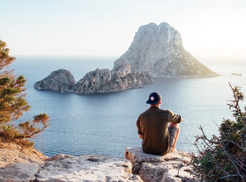 Rear View of Man Sitting on Rock by Sea