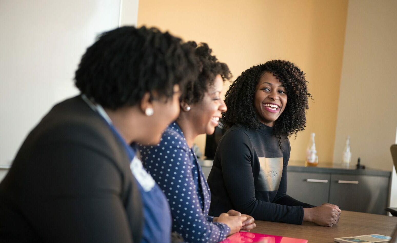 three women sitting beside wooden table